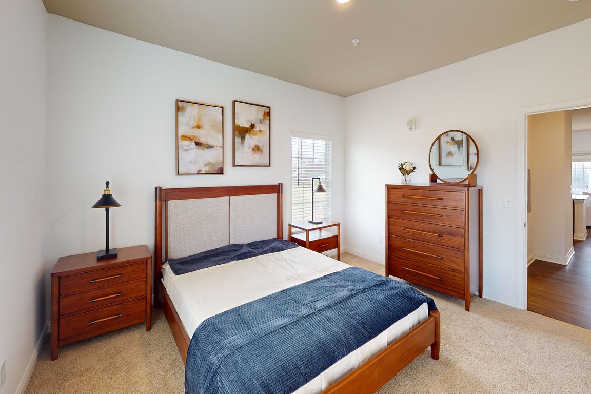 The Jane bedroom is spacious with natural light from windows on two walls.