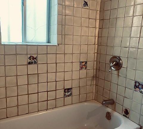 full bathtub with shower and Mexican tiles, with a westside window.