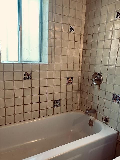 full bathtub with shower and Mexican tiles, with a westside window.