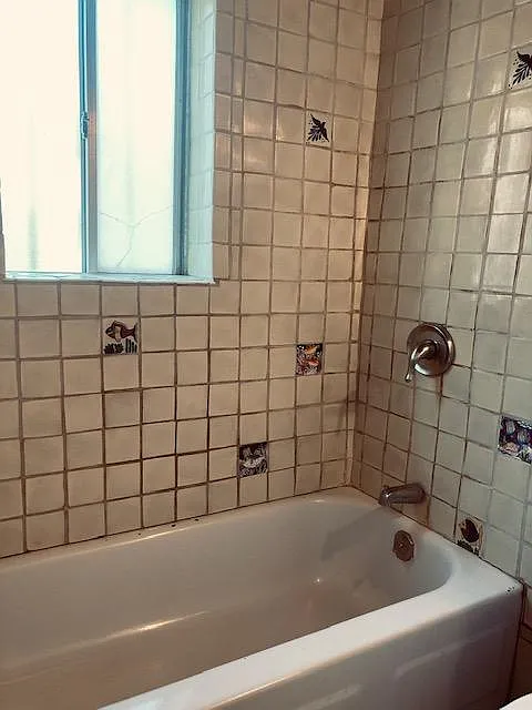 full bathtub with shower and Mexican tiles, with a westside window.