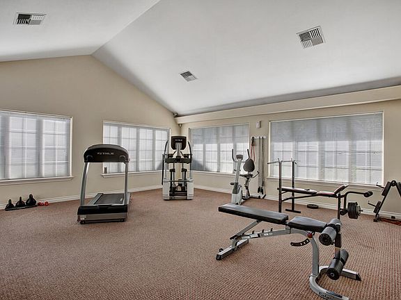 A large gym with a treadmill, elliptical, bike, and weights