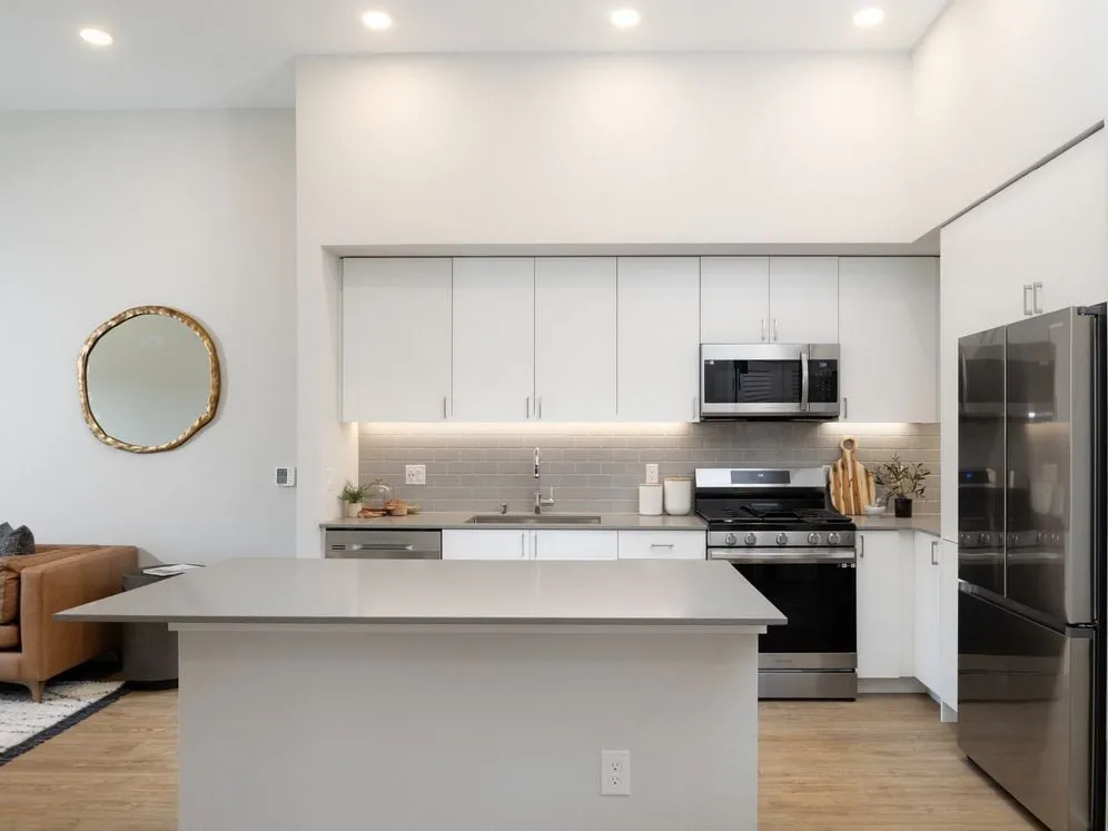 Kitchen with gray granite countertops, white cabinets, gray backsplash, stainless steel appliances and hard-surface flooring - Avalon Bothell Commons