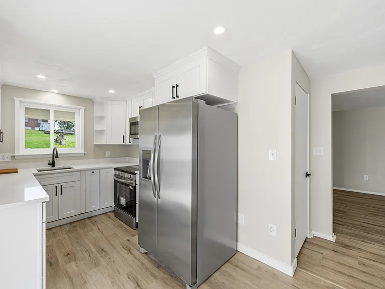 Renovated kitchen with stainless steel appliances, garbage disposal, quartz counters, undermount sink with custom inserts, soft-close drawers/door, and LED lighting.