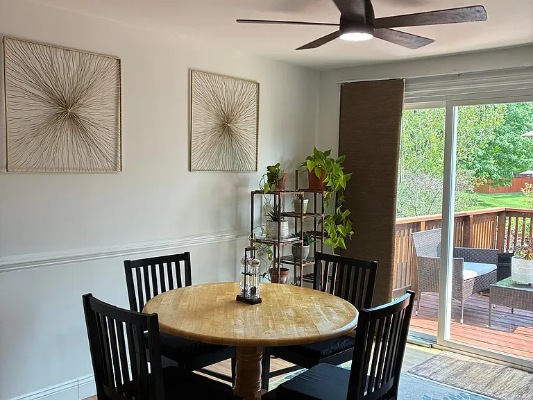 Open Dining Area with Deck Access: Bright, inviting dining space featuring a modern overhead ceiling fan. Large glass sliding doors open directly onto the back deck, seamlessly blending indoor dining with outdoor living for a more spacious feel.