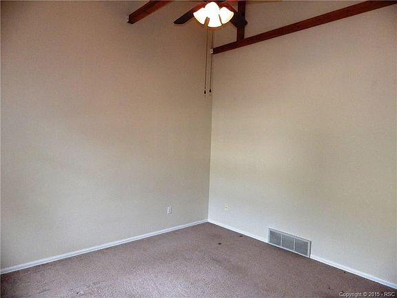Living room with vaulted ceiling, fan, and large windows that overlook the deck.