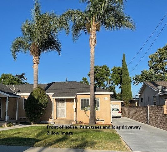 Front of house with front yard, palm trees and long driveway