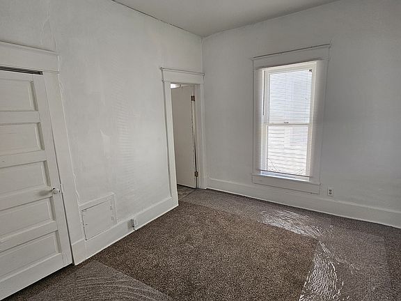 Bedroom Door on left of picture is to small lighted closet. Door by window is to bathroom