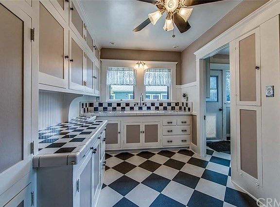 Kitchen has the original cabinets with the cooler and ironing board as well as new tile, new paint, and new flooring.  The laundry porch is at the right back and entry to the breakfast room is at the right front of the photo.