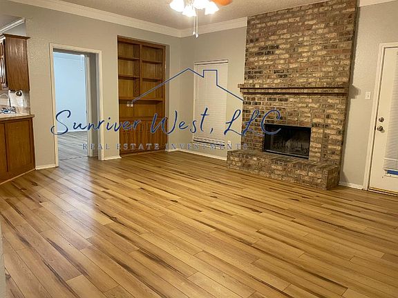 Living room with built-in storage, wood burning fireplace, and vinyl plank floors.