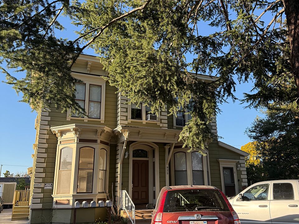 The unit can be entered via the stairway seen to the left of the house. The detached one car garage is not shown in this photo, but is to the left. Two additional spaces are also provided on the lot.