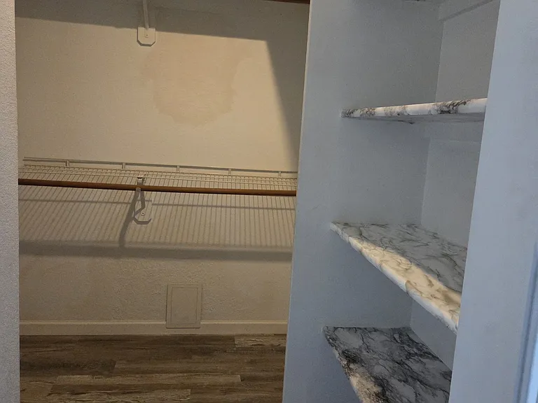 Doorway leading into the large master bedroom walk in closet with shoe shelves on the right.