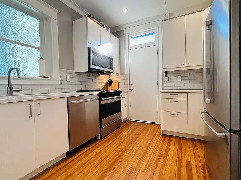 This modern kitchen is a chef's dream, featuring sleek subway tile backsplash and top-of-the-line appliances, including a refrigerator, filter watered and ice maker, disposal, dishwasher, and microwave.