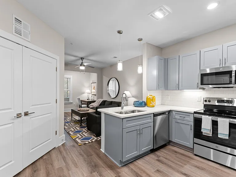 Active Adult kitchen and living room with white cabinets and stainless steel appliances