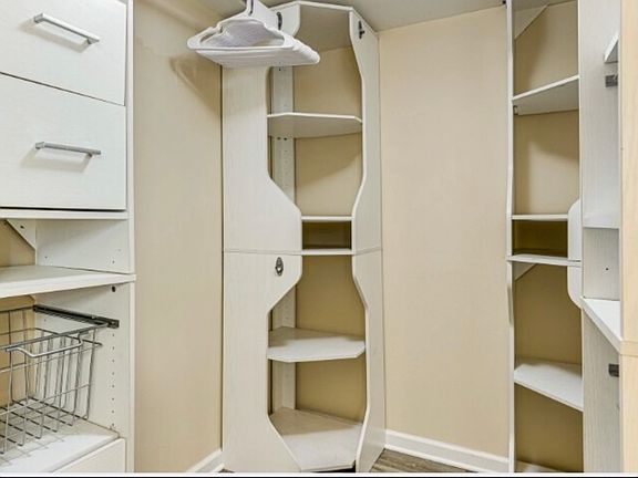 Spacious master bedroom with walk-in closet featuring built-in organizers for easy storage.