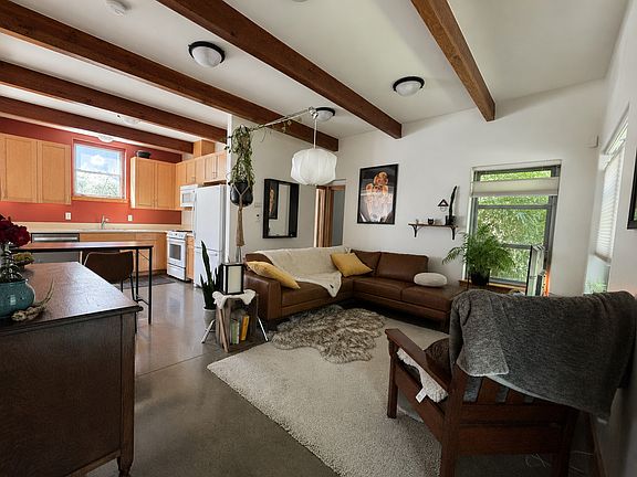 Living room shown from the entryway. Kitchen to the left. Down the hallway, a downstairs bedroom & large, full bathroom.