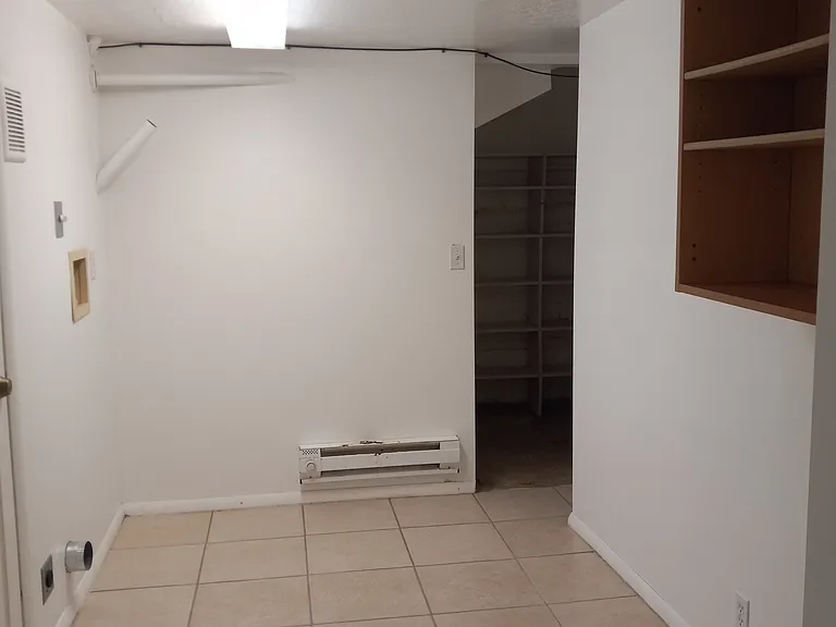 View from hallway into laundry room. Laundry hook ups shown. Walkway into food storage & utilities access visible.