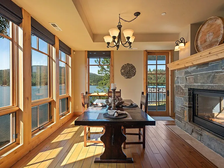 Dining area overlooking the water and view deck, two-way fireplace for cozy meals and ambience.