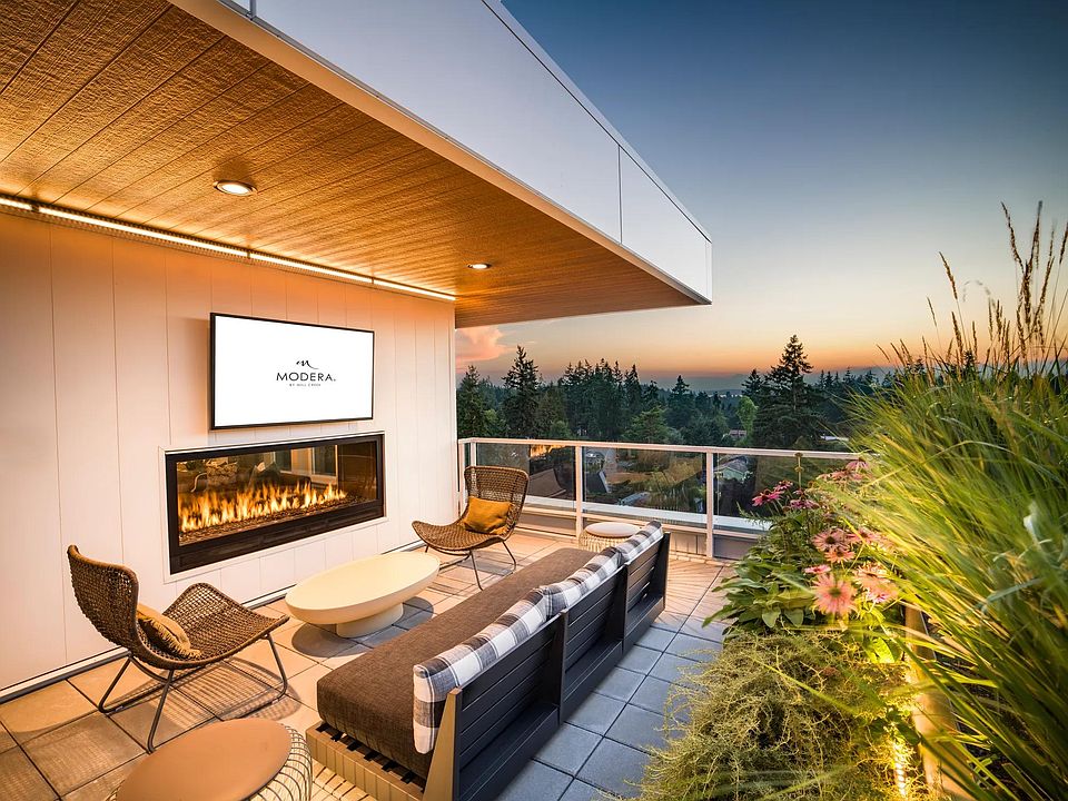 Take in the sunset from Modera Shoreline's rooftop terrace, featuring a cozy fireplace, lush greenery, and breathtaking views of the Pacific Northwest.