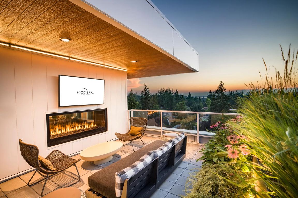 Take in the sunset from Modera Shoreline's rooftop terrace, featuring a cozy fireplace, lush greenery, and breathtaking views of the Pacific Northwest.