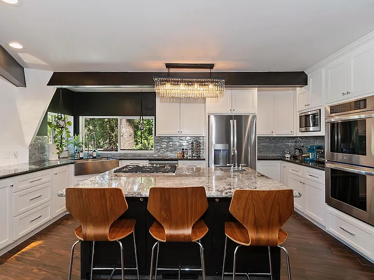 Kitchen with large island, prep sink and gas cooktop. 2 ovens