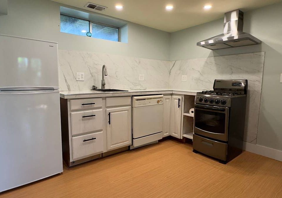 Kitchen with gas stove, refrigerator, outdoor vented hood, and dishwasher.