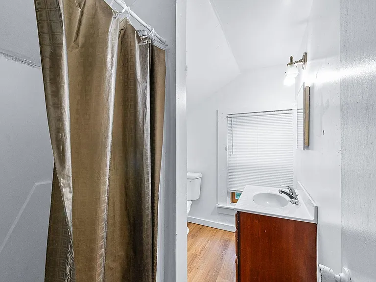 Full bathroom with tub/shower combo, vanity sink, and a window with blinds for ventilation and natural light.