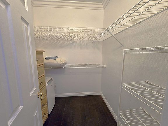 Walk-in closet with wraparound wire shelving and hanging space for organized storage.
