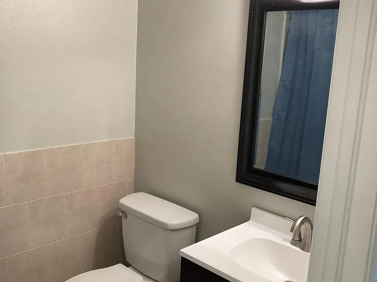Spare bedroom bathroom with new toilet, vanity, and mirror.