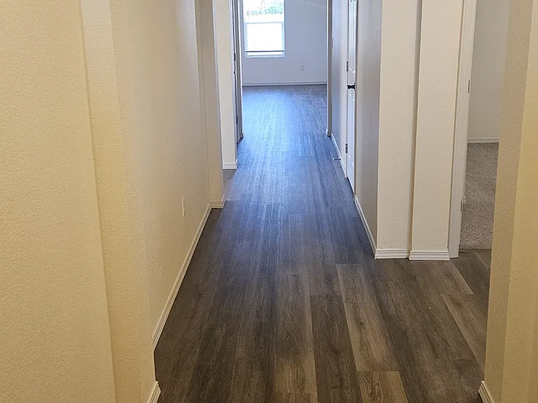 Hallway from the front door into the family room/kitchen. Two guest rooms and bath to the right