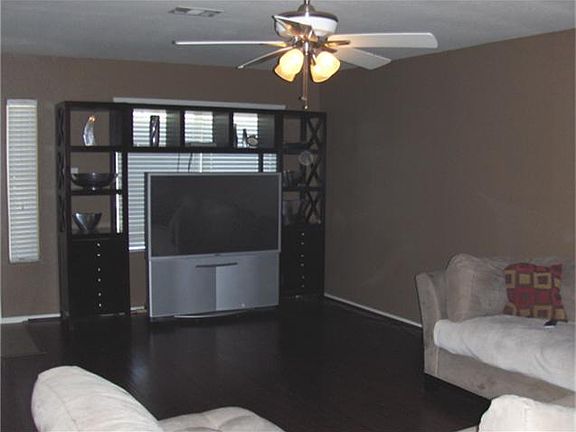 The den is very spacious and features wood flooring.