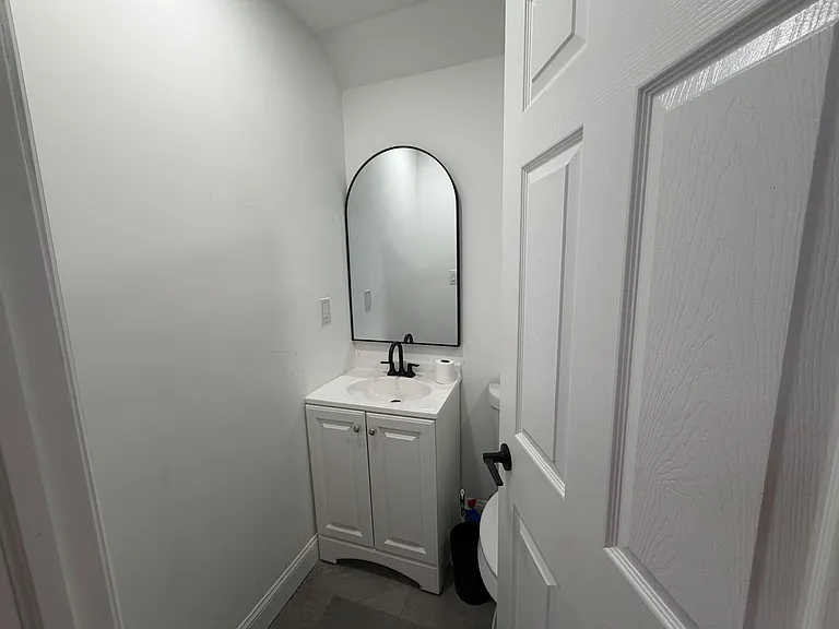 Bath with a pedestal-style vanity, framed mirror, and updated matte-black faucet for everyday convenience.