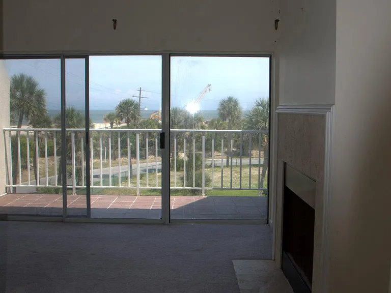 Primary bedroom view of empty room with fireplace, ocean view and covered balcon