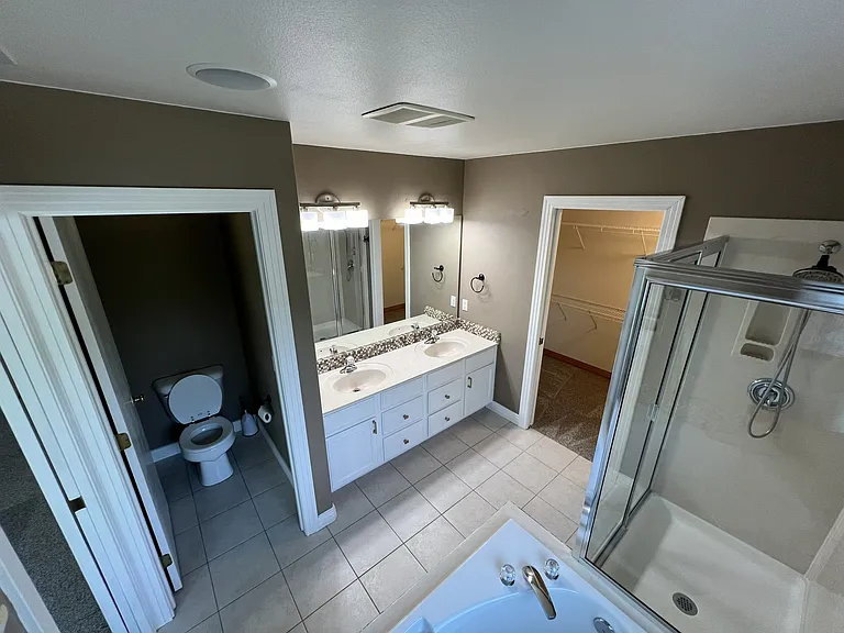Master Bathroom with water closet, shower, soaking tub, double sink vanity, and walk in closet