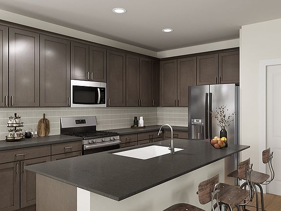 A modern, well-equipped kitchen with dark wood cabinets, stainless steel appliances, and a large cen