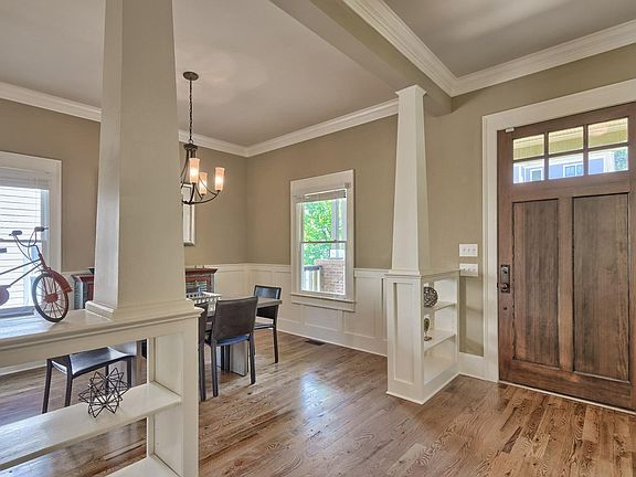 Enter through a wide wooden door into an open foyer with dining room to the right and living room/o