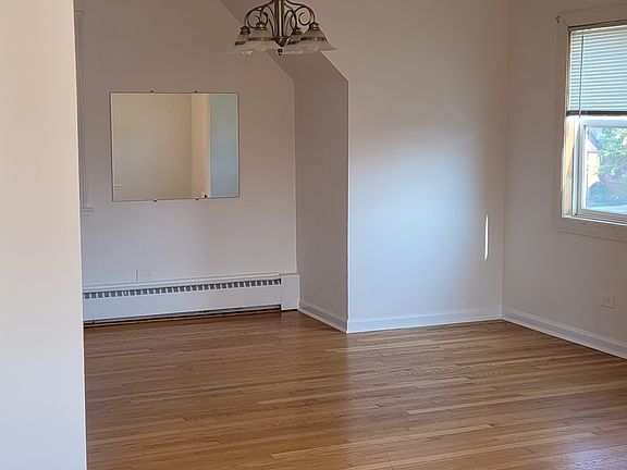 A bright, open sunny living room and dining room with hardwood floors.