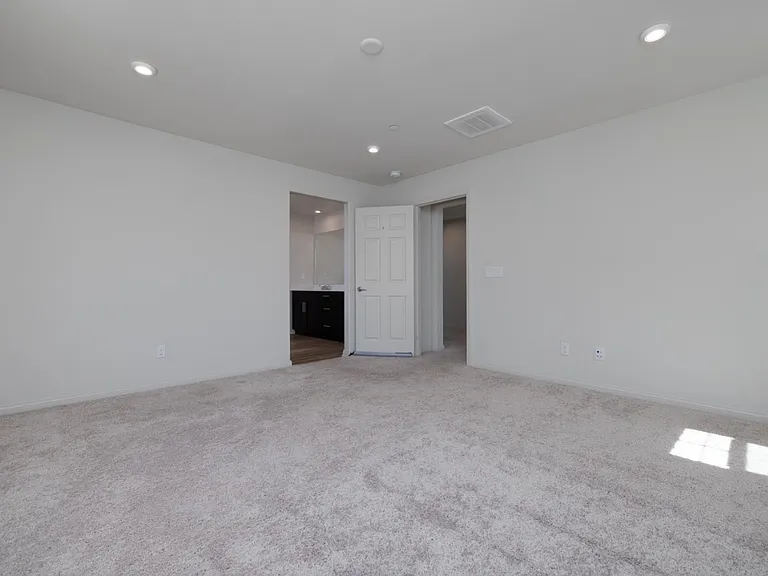 Spacious master bedroom located on the west-south corner, featuring soft carpet flooring and access to the second-floor hallway, private bathroom, and large walk-in closet. Bright natural light creates a warm and inviting retreat.