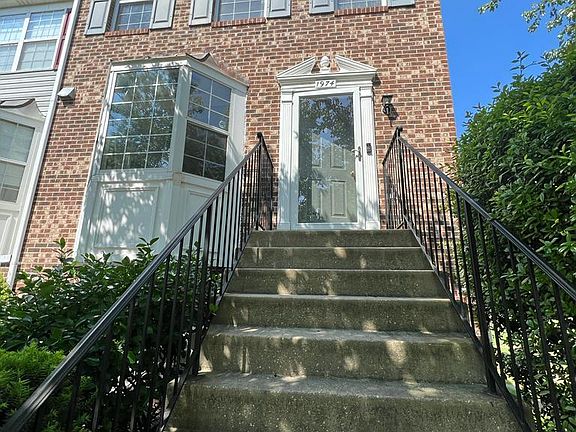 Front door entrance with storm door, stairs with railings.