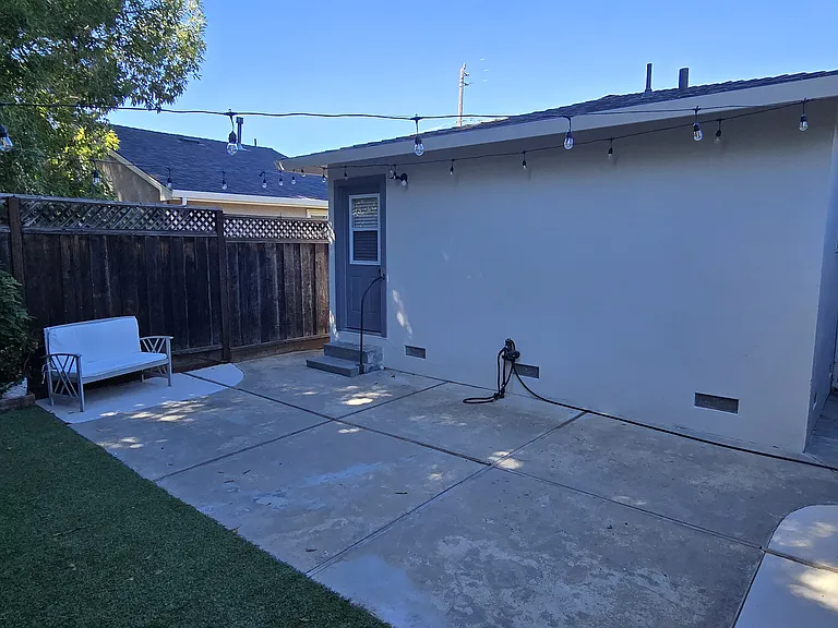 Large concrete patio area perfect for alfresco dining with neighboring mature shade trees.