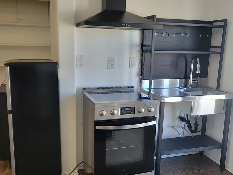 New range hood, electric stove with air fryer, and sink with rack.