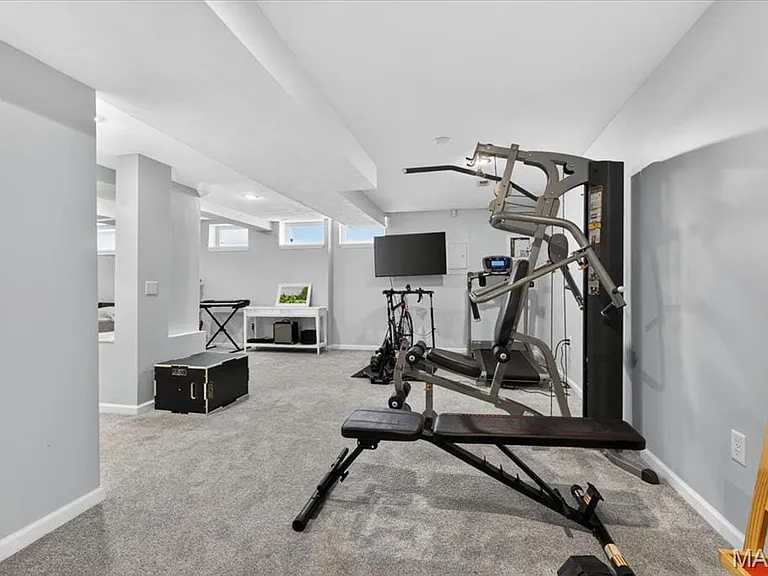 Spacious lower-level room featuring light gray carpeting, recessed lighting, white trim, and multiple egress windows