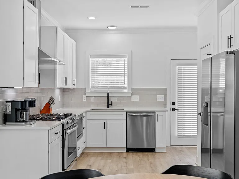 Streamlined kitchen with shaker cabinetry, gas range, stainless appliances, and a sink under the window for easy prep.