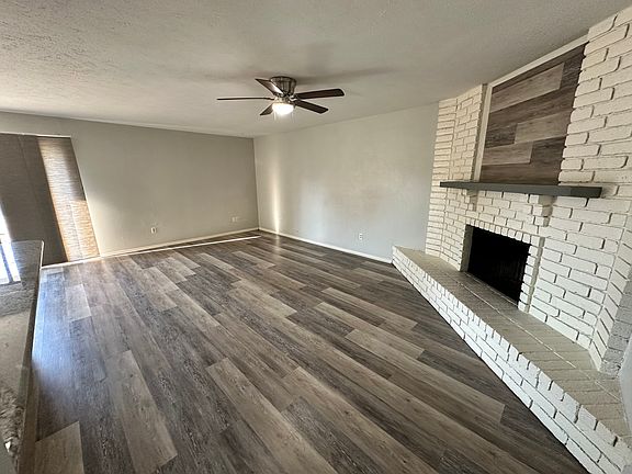 Living room with ceiling fan and wood burning fireplace.
