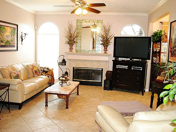 Family room with fireplace, tile floors, crown molding, and 2' faux wood blinds.