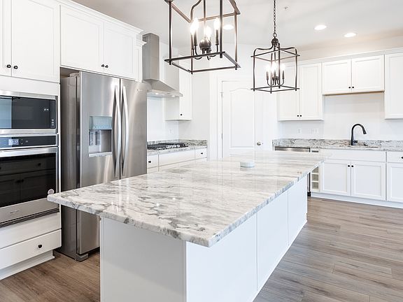 Kitchen with large island and stainless steel appliances in a DRB Homes Finch plan in Rosehill Manor