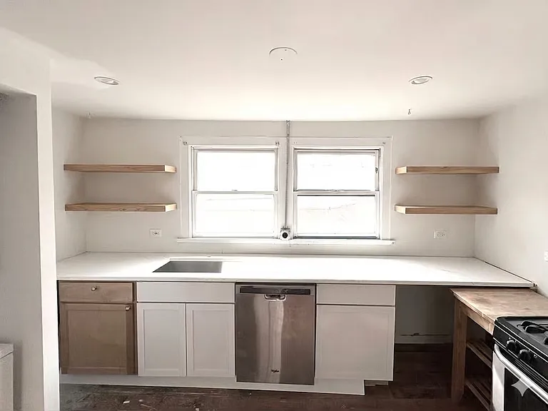 Kitchen with open shelving and quartz countertop. Gas range.