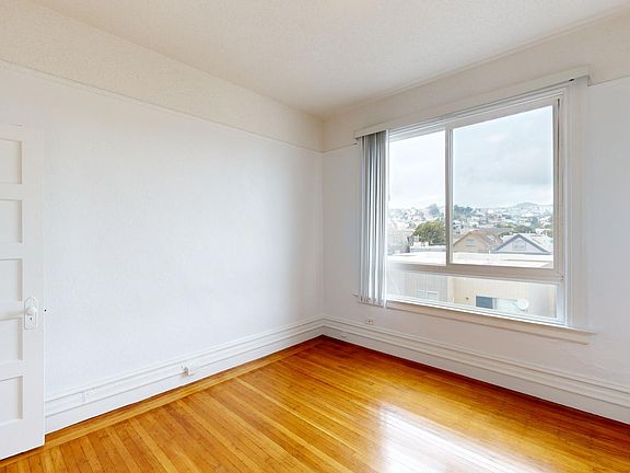 Bright bedroom with wood-like flooring and a large window
