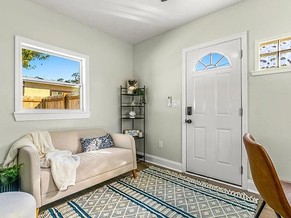 Main living space with front door, window, and mini-split AC