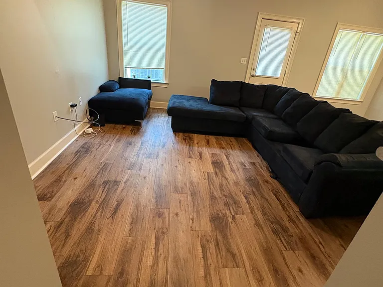 Living room with durable wood-look flooring, ceiling fan, and seating area with windows and a door for outdoor access.