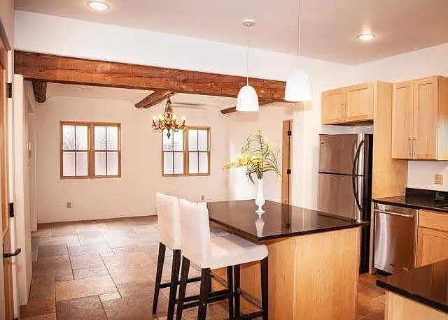 Chef's kitchen features large island w/ seating, tons of storage, newer stainless appliances, dishwasher, gas range, stone countertops. Dining area is in rear of this photo.